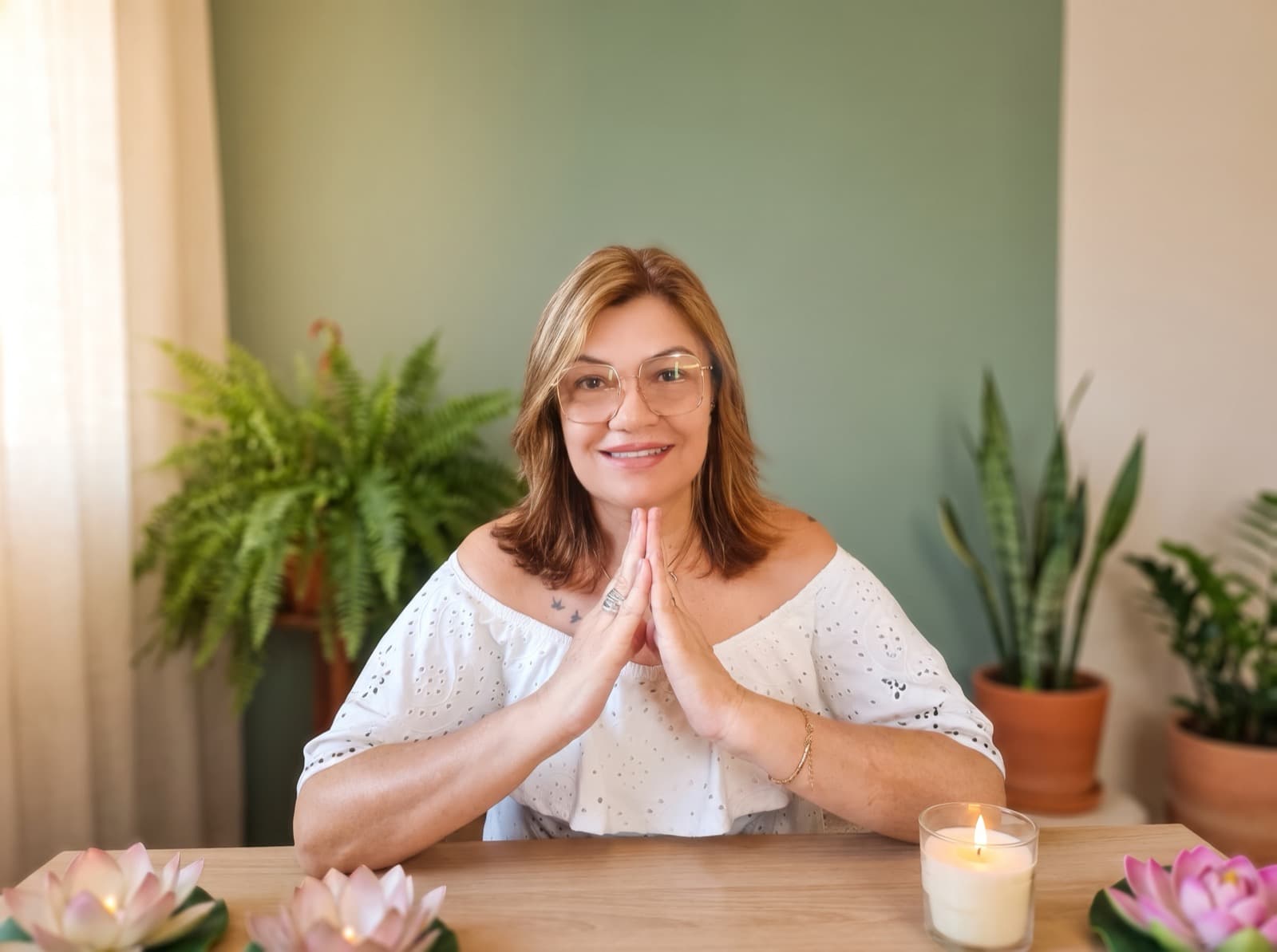 Cida Gomes, terapeuta integrativa, em gesto de acolhimento em seu espaço de atendimento